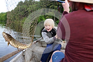 Happy Young Child Catching Northern Pike Fish in Boat