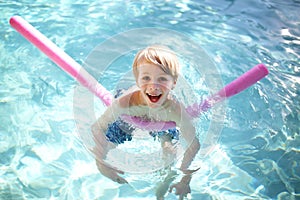 Happy Young Child Floating in Swimming Pool