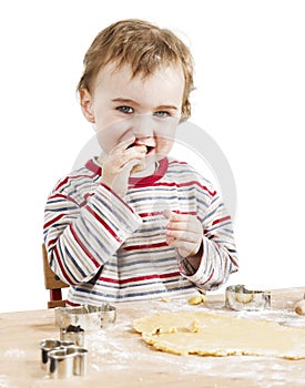 Happy young child nibbling dough in white background