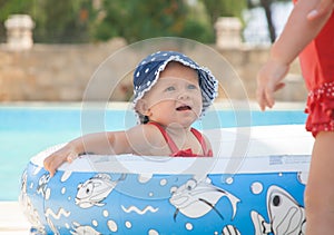 A happy young children is playing outside in a baby swimming pool