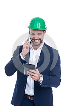 Happy young construction manager calling and using tablet isolated