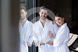 happy young couple in bathrobes smiling at camera