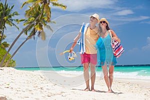 happy young couple with beach accessories having fun by the beach