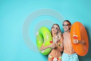 Happy young couple in beachwear with inflatable rings