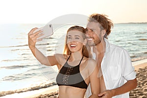 Happy young couple in beachwear taking selfie