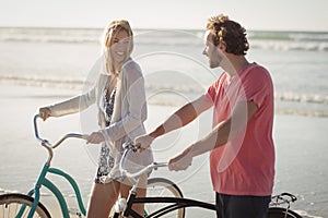 Happy young couple with bicycles at beach