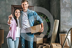 happy young couple with boxes and key moving into