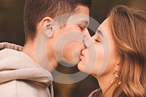 Happy young couple boy and girl kissing each other together outdoors. Romantic feelings