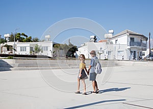 Happy young couple of boyfriend and girlfriend in love leisurely stroll through the city