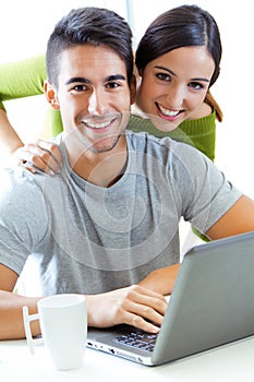 Happy young couple browsing internet at home