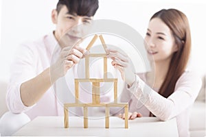 Happy young couple building house by with wooden bricks for home concept