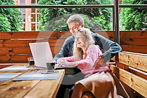 Happy young couple in a cafe behind a laptop. the guy and the girl have fun smiling