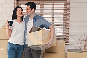 Happy young couple Carrying cardboard boxes and walking from the front door into the house in a new house at moving day. Concept