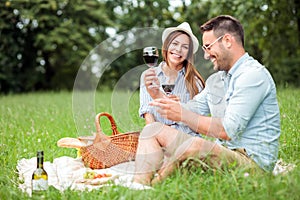 Happy young couple celebrating anniversary or birthday by having a romantic picnic in park