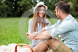 Happy young couple celebrating anniversary or birthday by having a romantic picnic in park