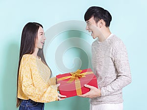 Happy young couple celebrating for chinese new year and holding gift box.Isolated on blue background