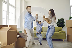 Happy young couple with child having fun in living room in their new home on moving day