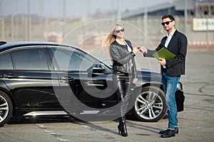 Happy young couple chooses and buying a new car for the family.