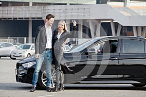 Happy young couple chooses and buying a new car for the family.