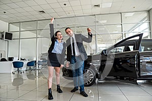 happy young couple chooses and buys a new car for the family at a car dealership.