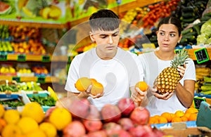 Happy young couple chooses fruits