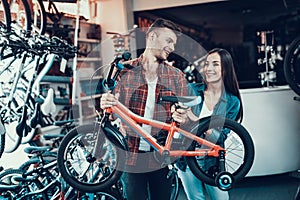 Happy Young Couple Chooses Kids Bicycle in Store