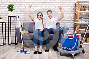 Happy Young Couple With Clenched Fist Sitting On Sofa