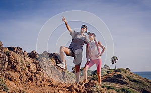 Happy young couple climbs to the top in the mountains near the ocean