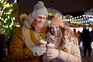 Happy young couple with coffee at christmas market