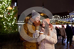 Happy young couple with coffee at christmas market