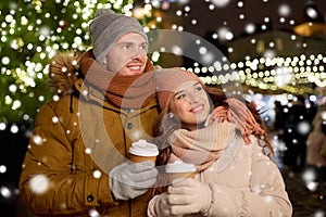 Happy young couple with coffee at christmas market