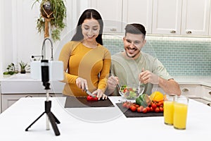 Happy young couple cooking dinner together at home, taking selfie