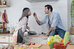 Happy young couple cooking together in the kitchen, feeding each other in their kitchen at home