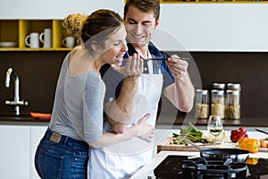 Happy young couple cooking together in the kitchen at home.