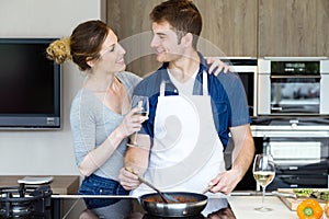 Happy young couple cooking together in the kitchen at home.