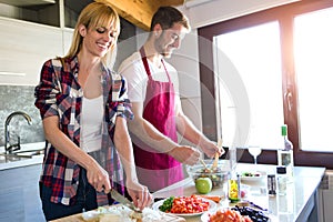 Happy young couple cooking together in the kitchen at home.