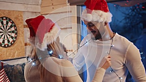 Happy young couple dancing with christmas lights and santa hats. Love and affection during the christmas eve