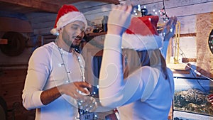 Happy young couple dancing with christmas lights and santa hats. Love and affection during the christmas eve