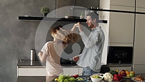 Happy young couple dancing in kitchen. Caucasian family in casual clothes having fun dance together, enjoying happy