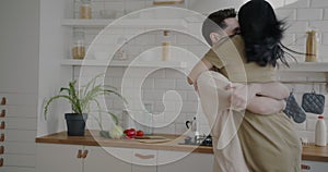Happy young couple dancing in kitchen hugging expressing love enjoying time together