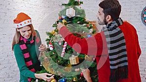 Happy young couple decorating and preparation ornament on Christmas tree together with enjoy at home.