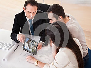 Happy Young Couple Discussing With Consultant