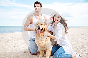 Happy young couple with dog sitting on the beach