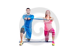 Happy young couple doing exercise in pair with elastic rubber for pregnancy on the white background