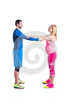 Happy young couple doing exercise in pair for pregnancy on the white background