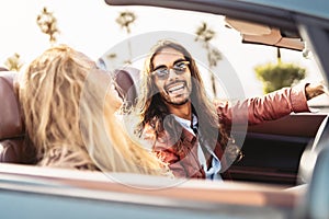 Happy young couple doing road trip in tropical city - Travel people having fun driving in convertible car discovering new places