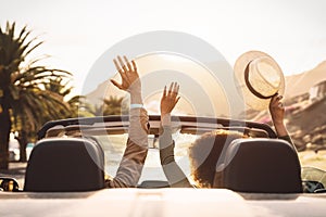 Happy young couple doing road trip in tropical city - Travel people having fun driving in trendy convertible car