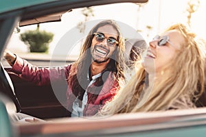 Happy young couple doing road trip in tropical city - Travel people having fun driving in trendy convertible car