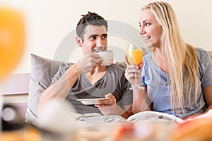 Happy young couple drinking coffee and orange juice