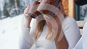 Happy young couple drinking hot chocolate on the balkony on winter day. Christmas or valentines day